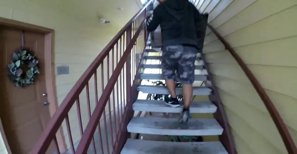Second-floor walk-up delivery on a narrow wooden stairwell