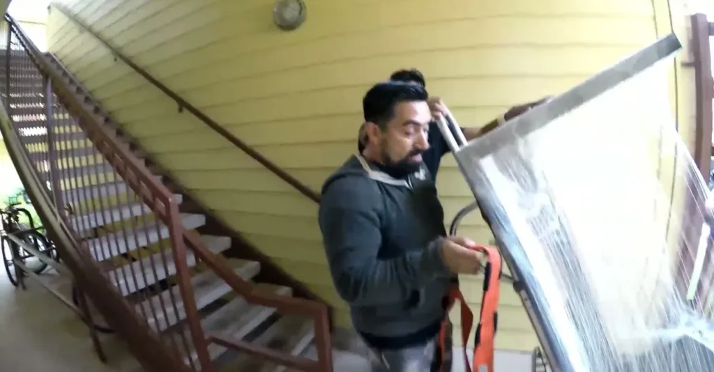 Mover guiding a stretch-wrapped load on a hand truck by the stairwell in Oxford